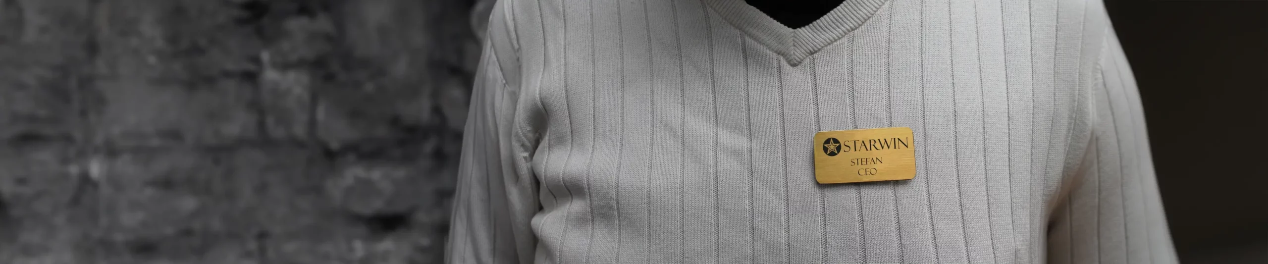 Ein Mann mit einem gravierten Namensschild aus Messing auf seinem Hemd