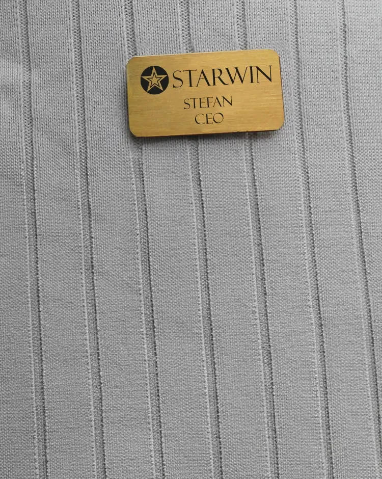 Ein Namensschild aus Messing mit Firmenname, Personenname und Titel.